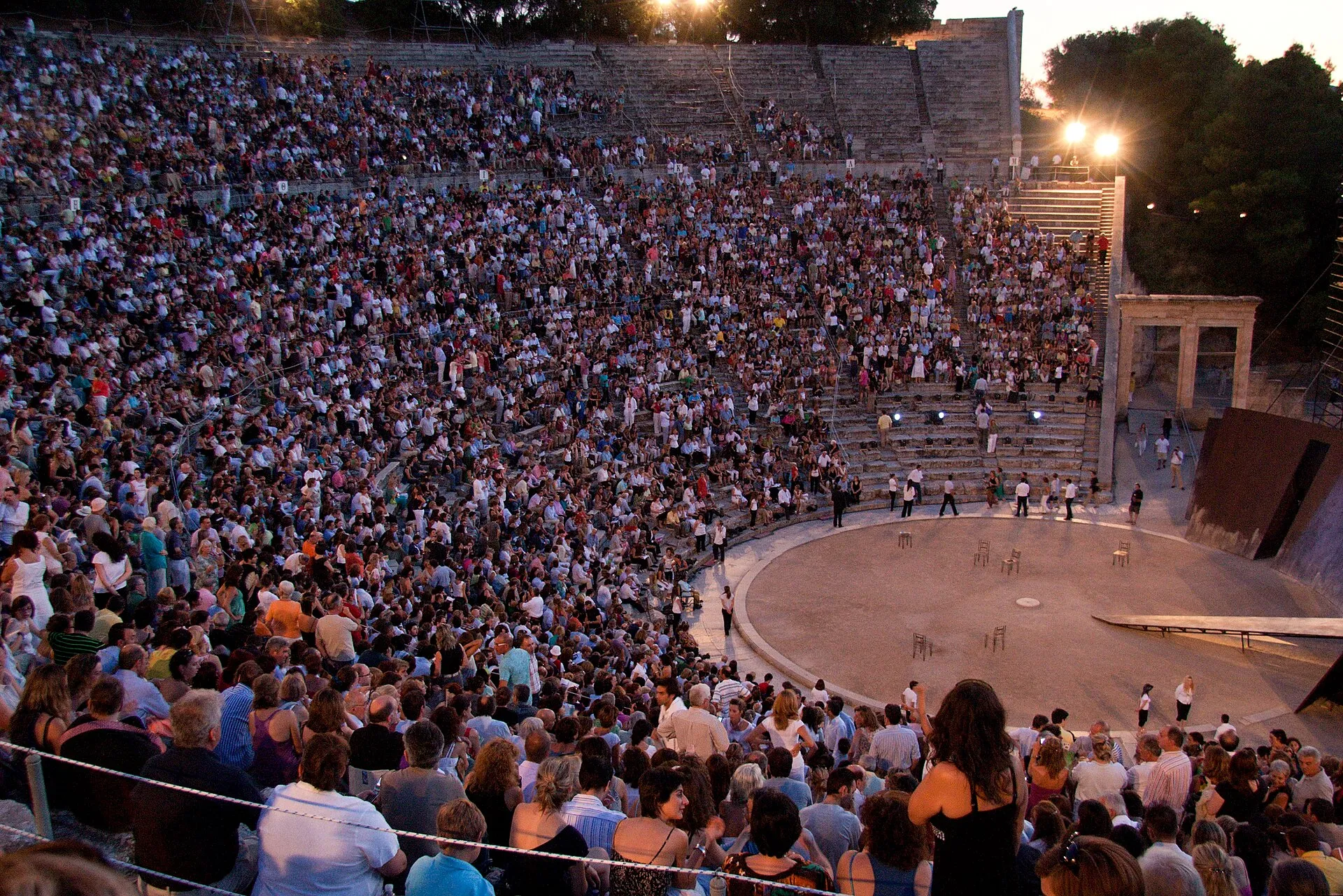 Il teatro di Epidauro gremito di pubblico durante uno spettacolo serale